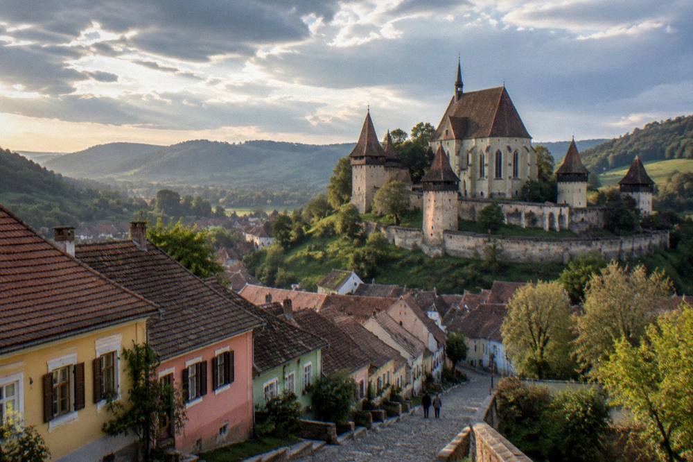Panorama of coloured historic houses on a hillside street under an evening sky