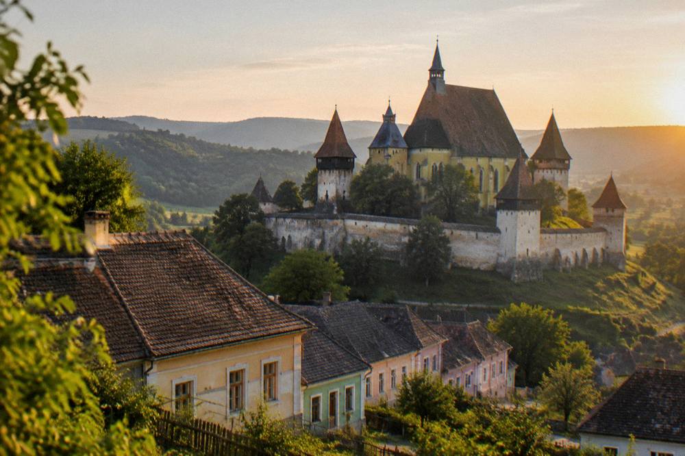 Fortified church towers rising above trees and countryside at sunset