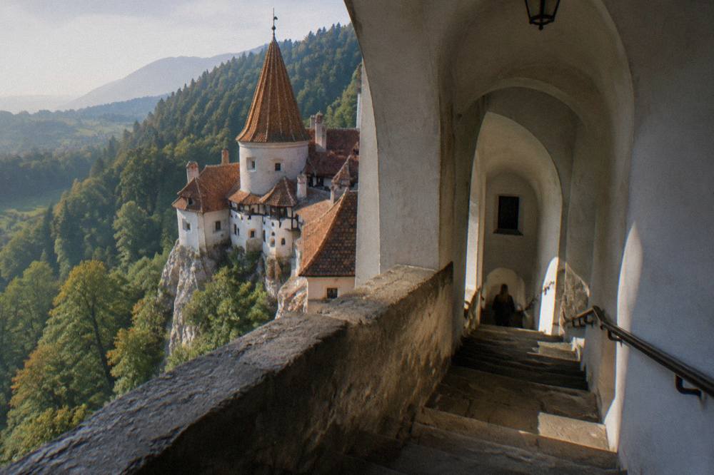 A narrow stone staircase inside Bran Castle with arched doorways and worn steps