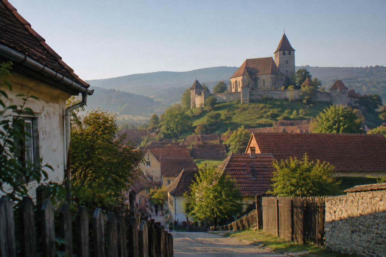 A fortified Saxon church with a stone tower standing above red rooftops in a Transylvanian village