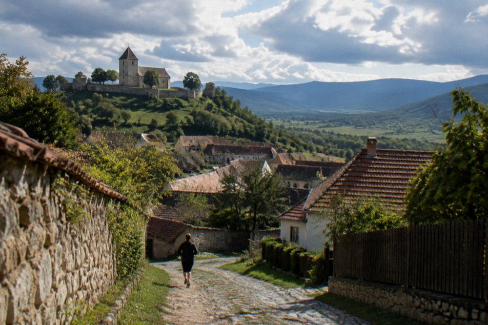 Panoramic view over village rooftops toward distant blue Transylvanian hills