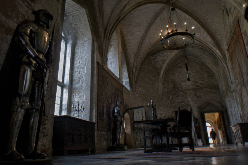 A stone vaulted hall inside Corvin Castle with armour and period furnishings