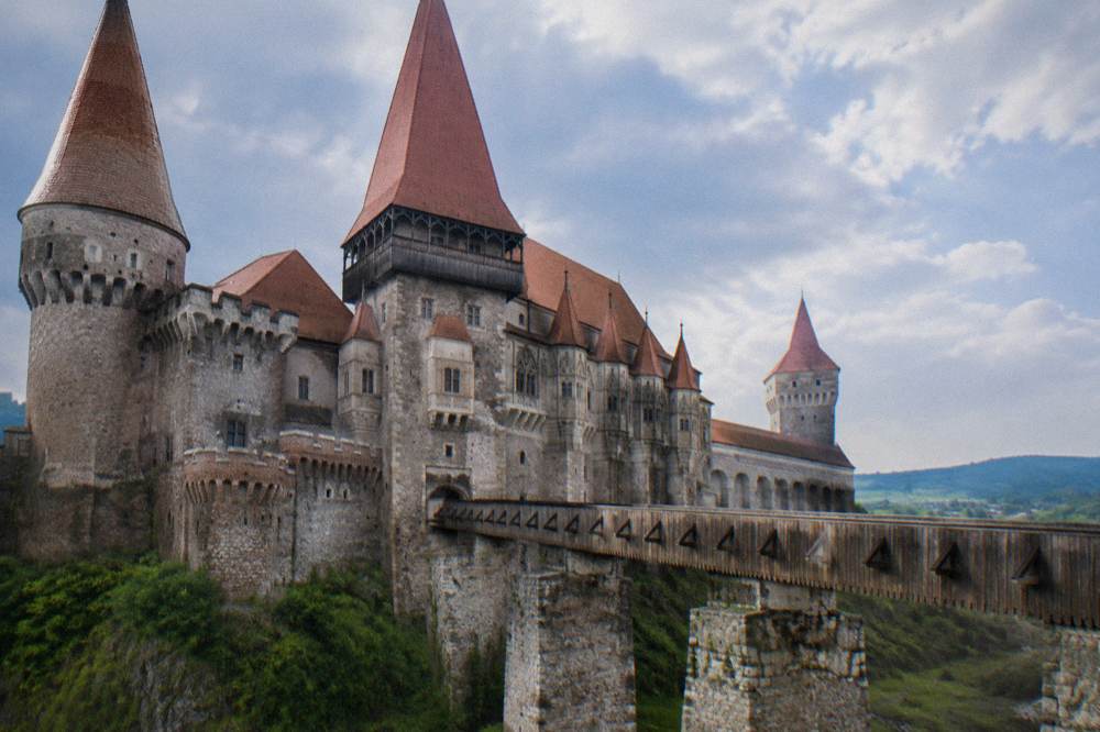 Close view of Corvin Castle's pointed towers and red roofs against the sky