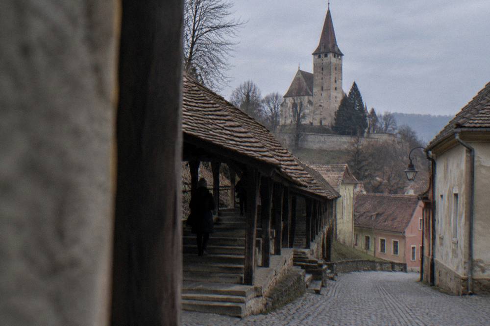 A covered wooden staircase climbing a hill towards a church in an old town