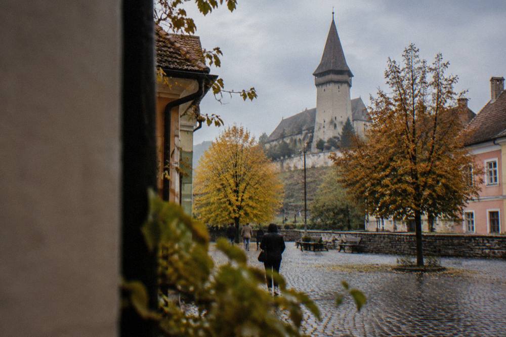 Autumn trees and cobblestones in a small Transylvanian square under an overcast sky