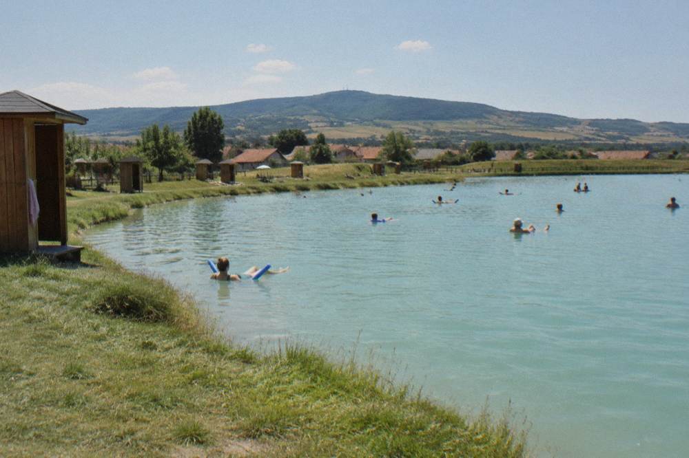People floating on bright turquoise water in a salt lake bordered by grass