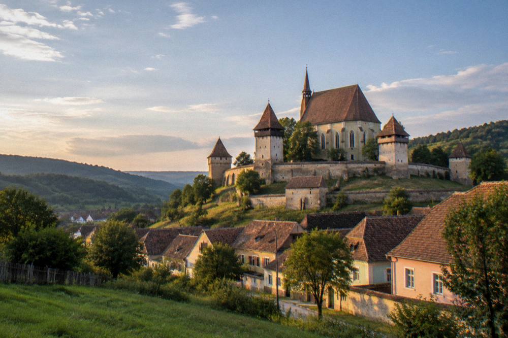 A fortified church on a hill above a Transylvanian village at golden hour