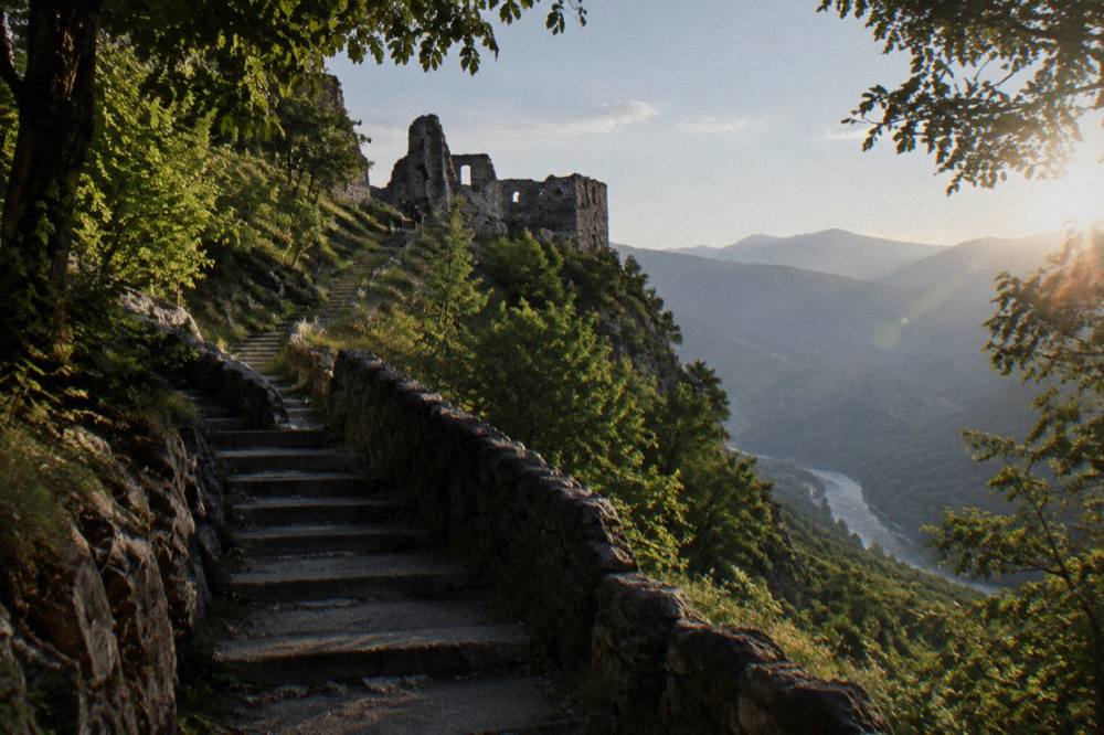 Steep concrete and stone stairs climbing a green forested slope toward a ridge