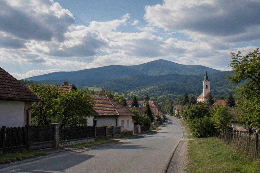 Country road climbing from Sibiu toward Rășinari with the Cindrel foothills in the background