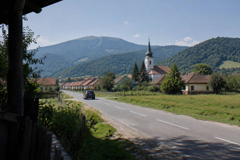 Car driving along Calea Rășinari with open meadows on either side