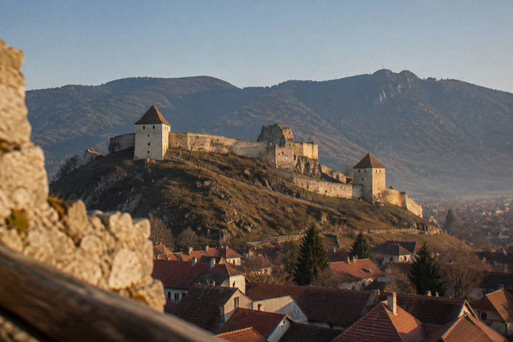 Fortress walls and towers under a clear blue sky above a valley town
