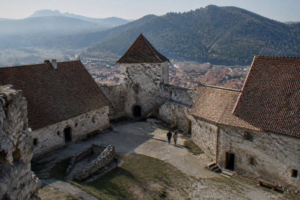 A courtyard of stone buildings inside a hilltop fortress on a sunny afternoon