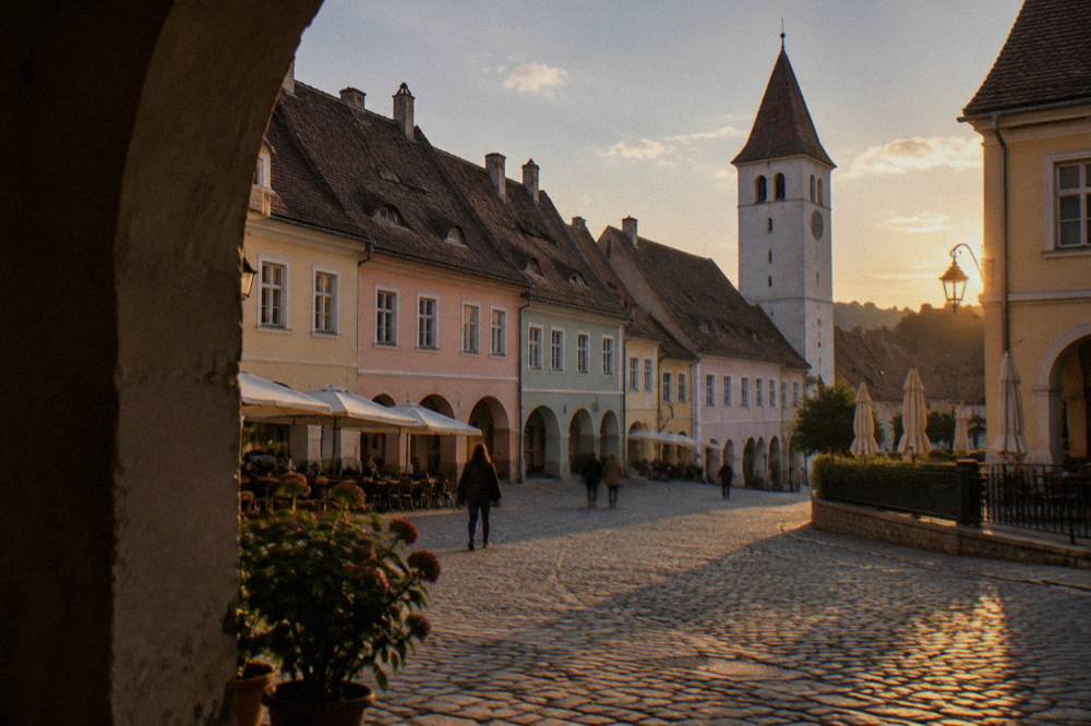 Pastel coloured burgher houses with tall gabled roofs enclosing a small square in Sighișoara