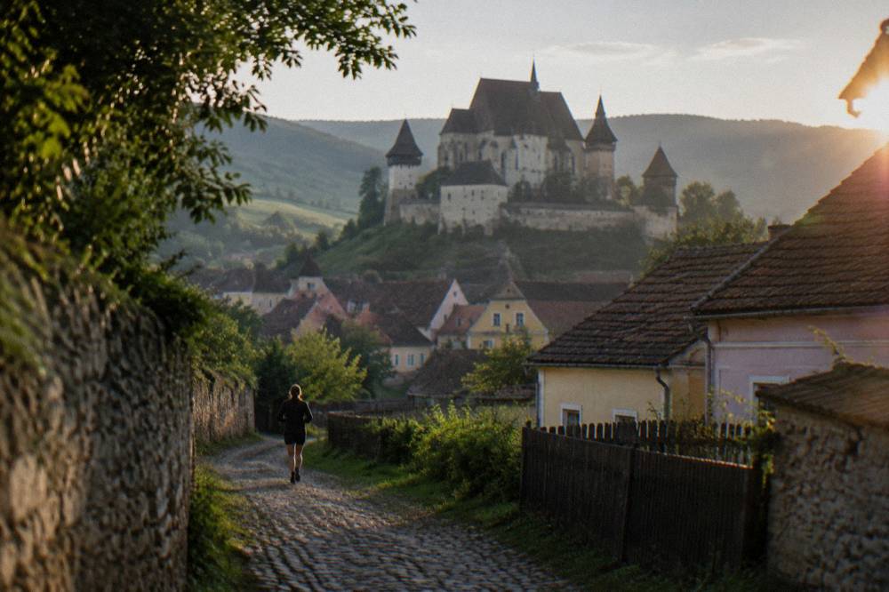 A stone fortified church with heavy walls and towers standing above a Transylvanian village