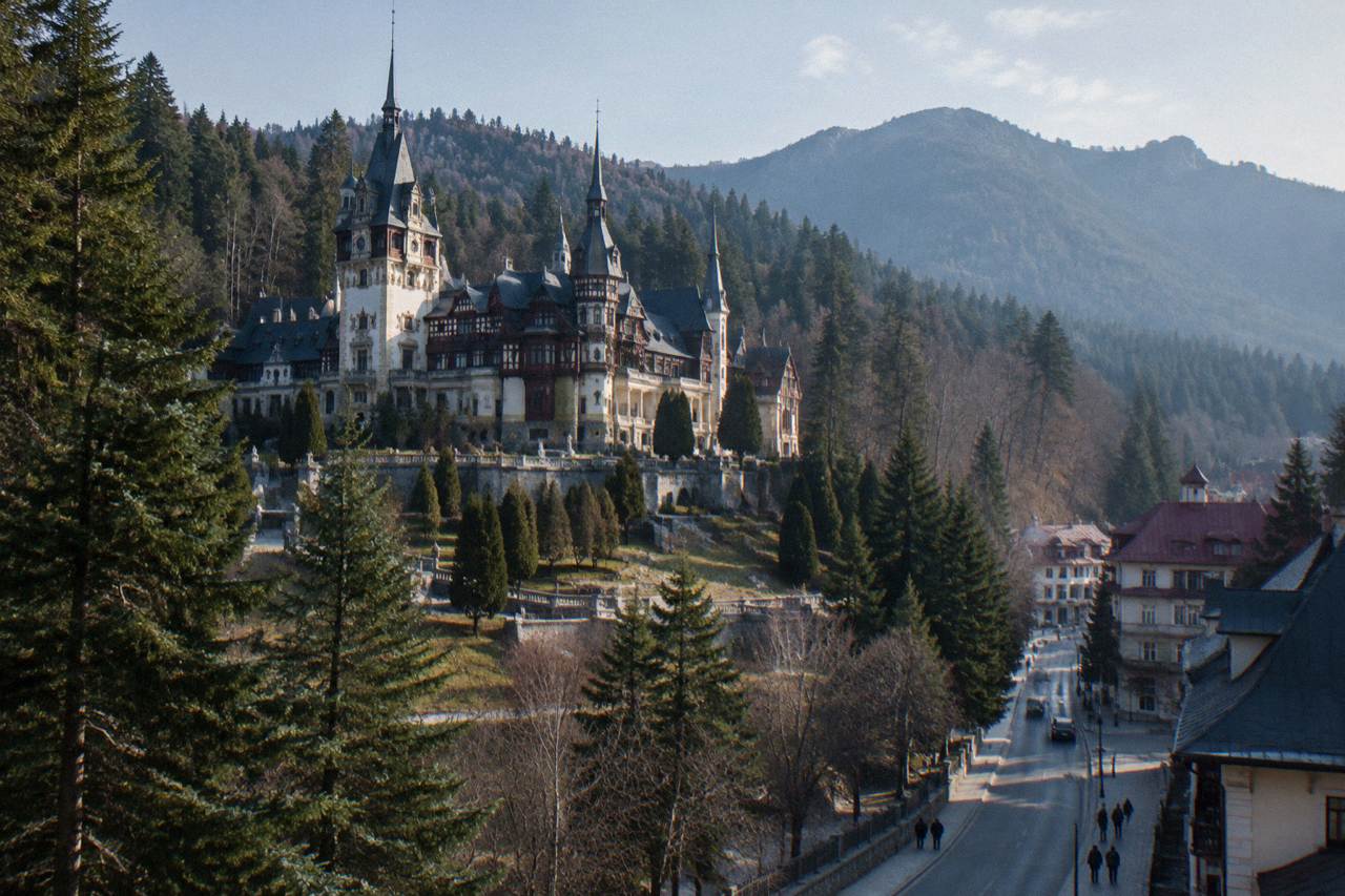 A mountain town street in Sinaia with forested Carpathian slopes rising behind the buildings