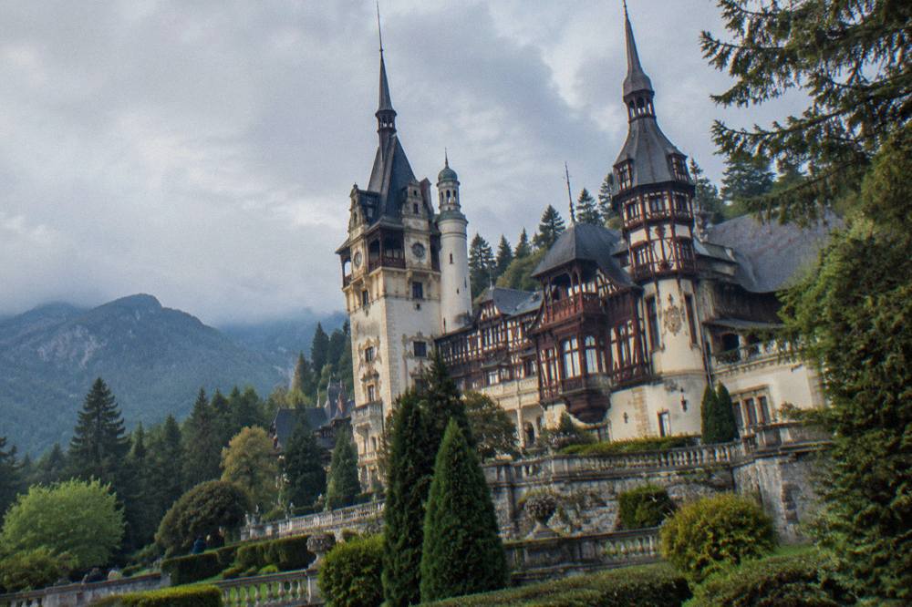 A Neo-Renaissance castle facade with ornate towers and carved stonework set among fir trees