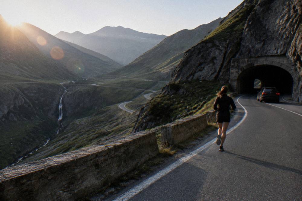 A car on a high mountain road with a tunnel entrance and rock walls