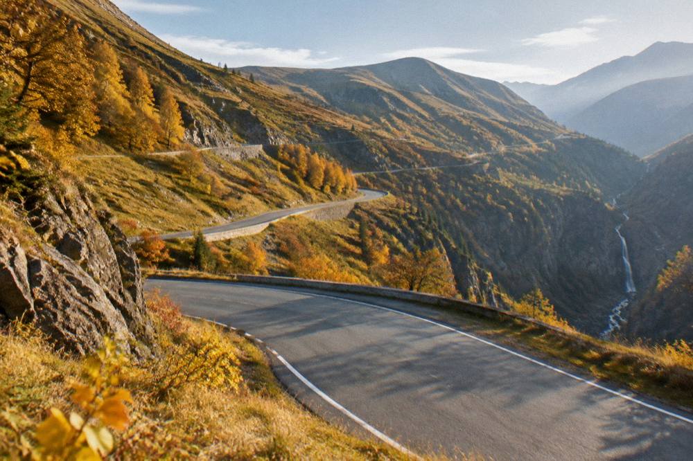 An empty switchback mountain road in autumn light with golden slopes