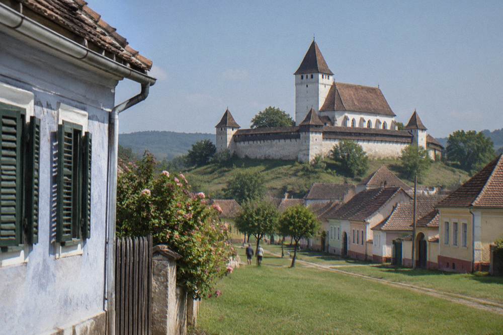 A thick defensive church wall with a narrow wooden walkway and small tower openings
