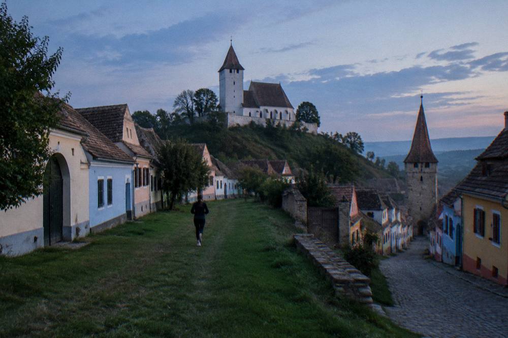 Colourful burgher houses on a narrow cobbled street below a clock tower