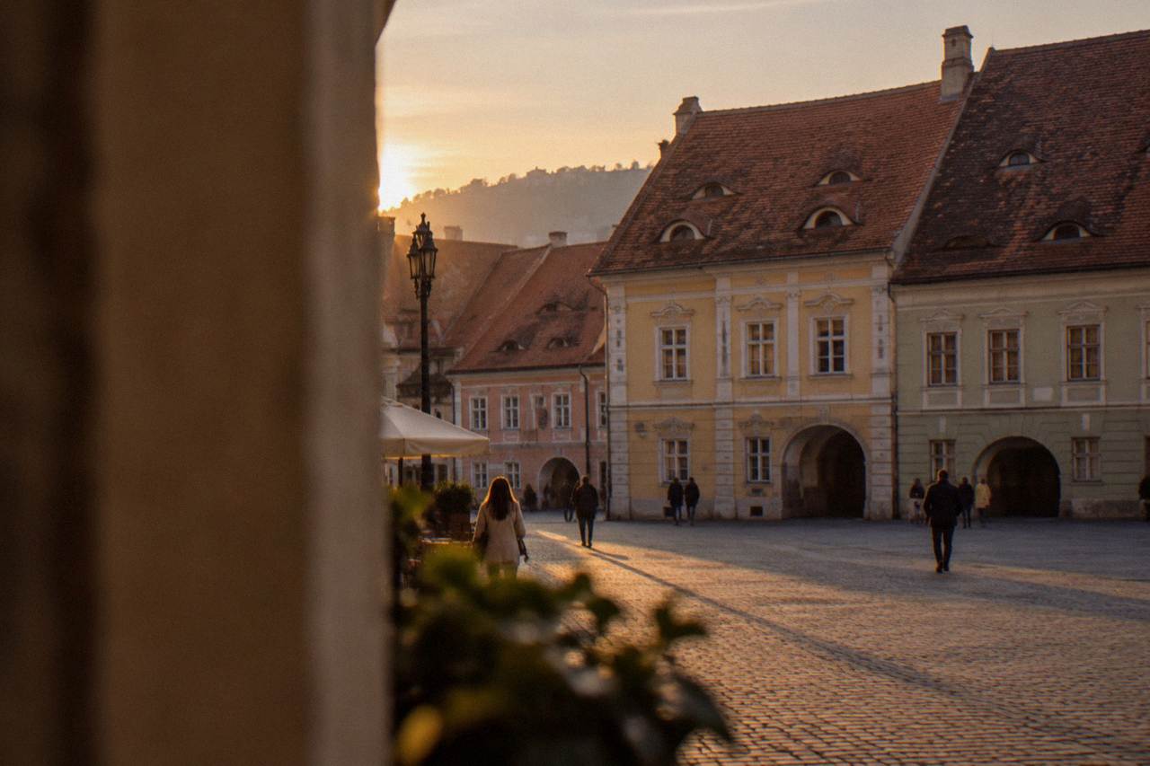 Colourful historic houses with steep roofs above a cobbled square in Sibiu at dusk