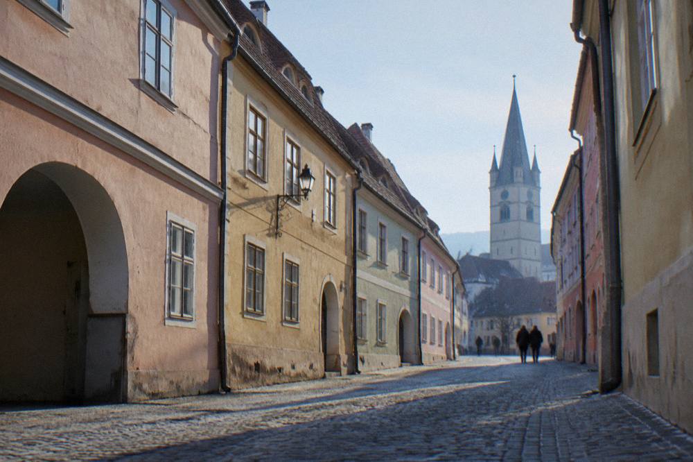 A narrow cobbled street lined with pastel-coloured old town houses in Sibiu