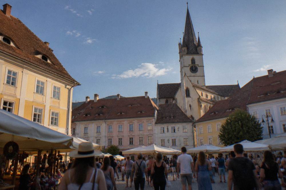 Crowds and market stalls filling a large town square at a summer festival in Sibiu