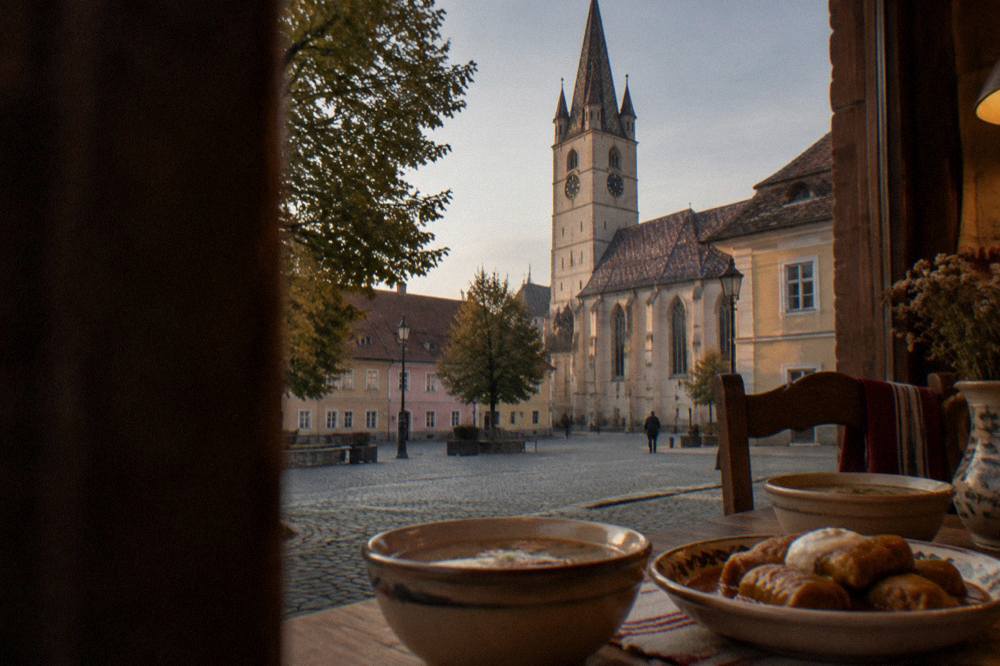 Bowls of sour soup and cabbage rolls on a wooden table in a traditional Romanian kitchen