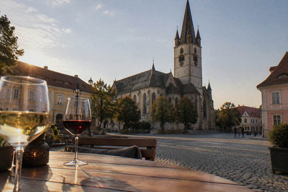 A terrace table with glasses of wine in warm evening light beside a historic building