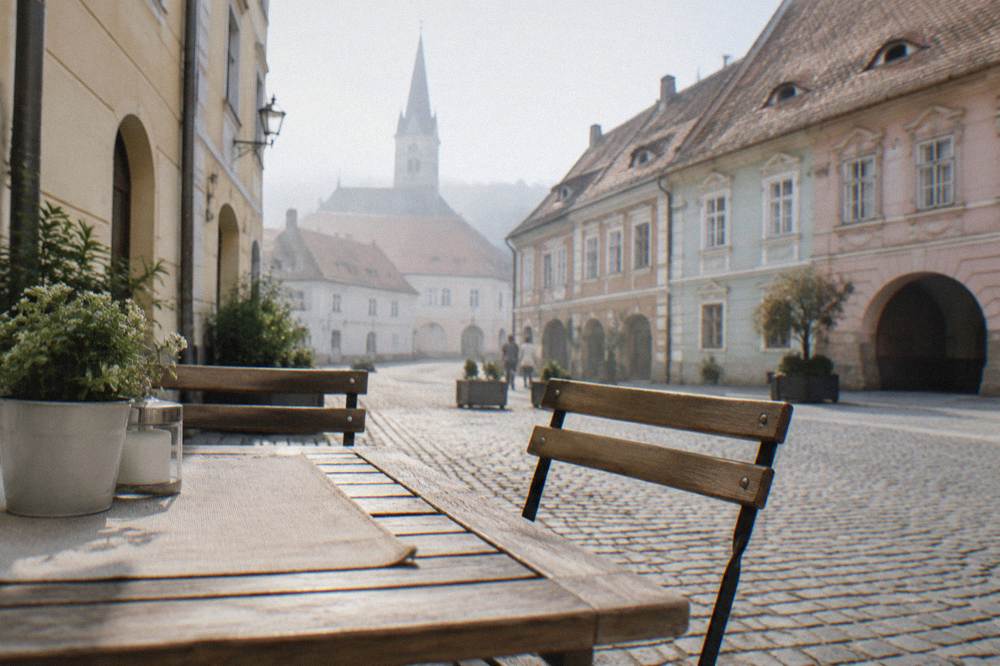A set restaurant table on a quiet old town lane, chairs empty