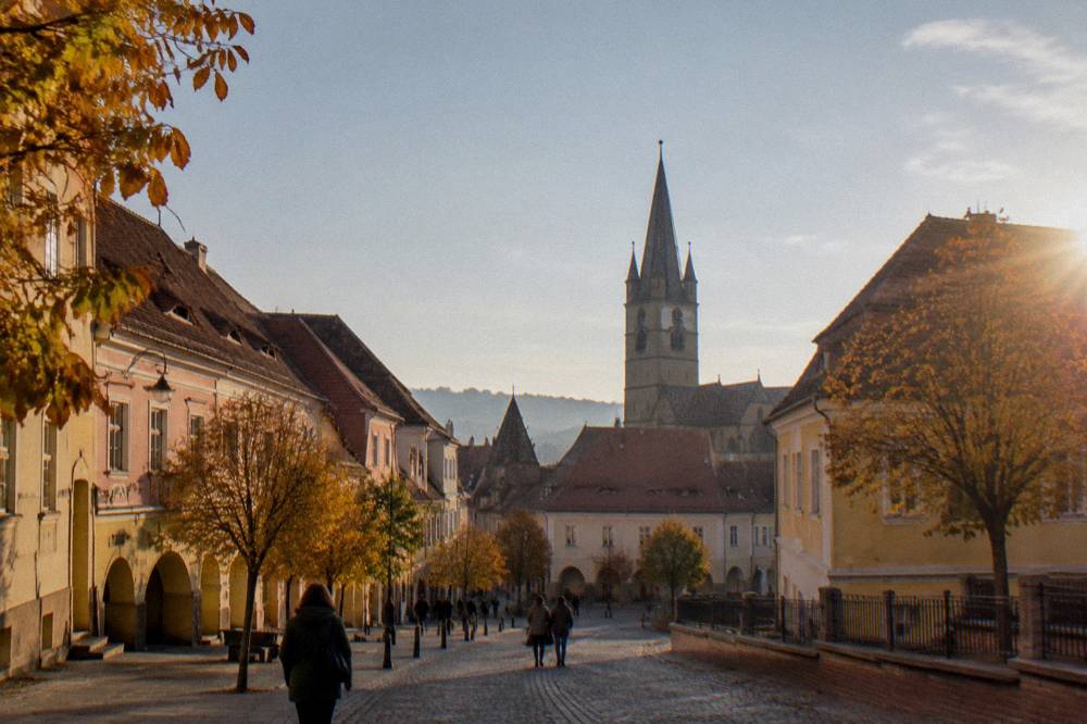 Autumn trees and historic buildings along a street in Sibiu old town