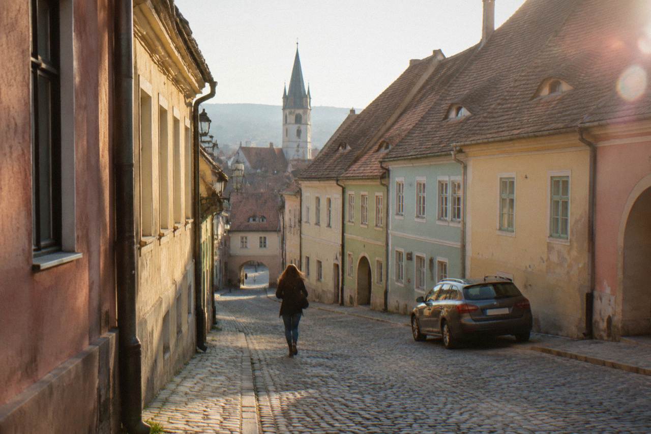 A parked car on a quiet street of coloured old houses in the Sibiu old town