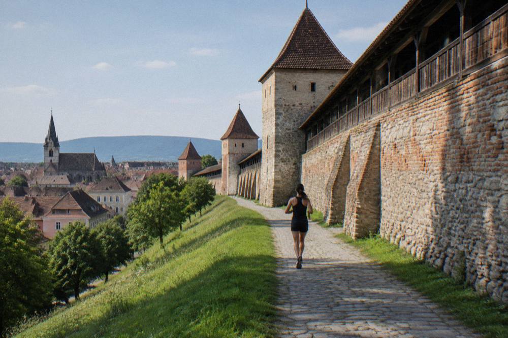 Thick stone church fortification walls with wooden walkways in a green Transylvanian village