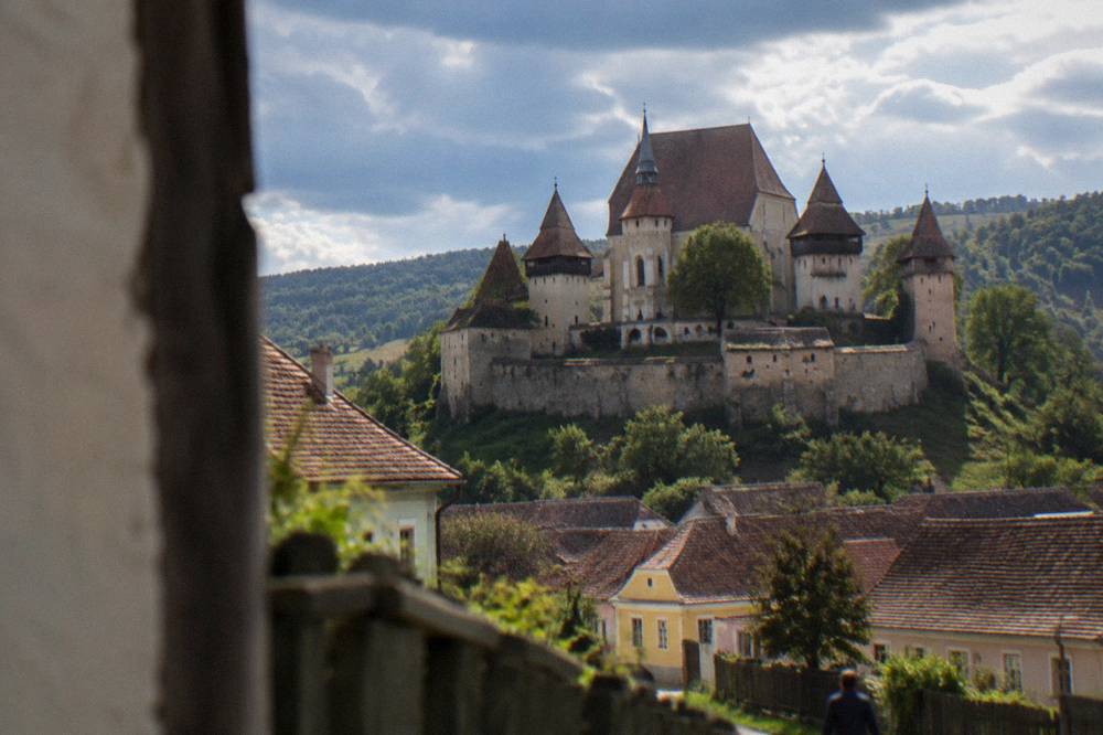 A small hilltop fortified church enclosed by stone walls above a village near Sibiu