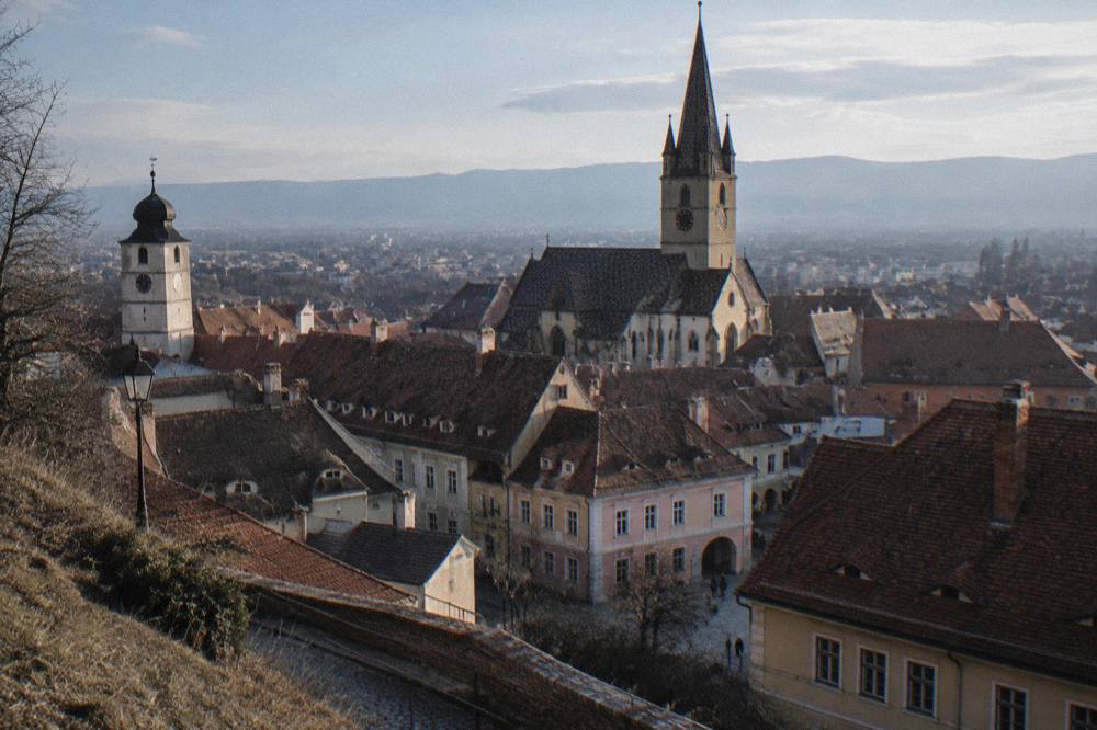 Rooftops and church towers of Sibiu seen from a hillside above the city