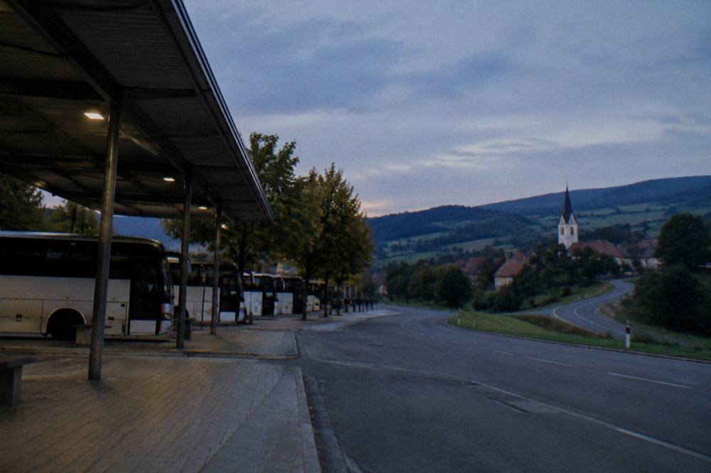A country road winding through green Transylvanian hills toward a village with a church tower