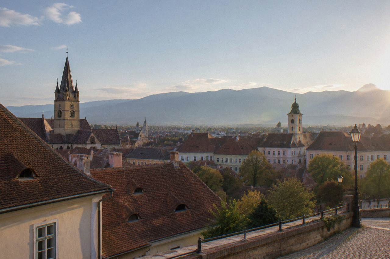 A view over Sibiu's old town rooftops with church towers and the Carpathian mountains behind