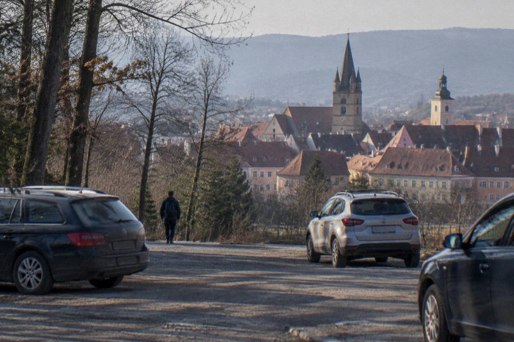 A parking area with a few cars at the edge of a forest on the outskirts of Sibiu