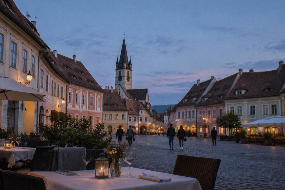 A table set for dinner on a pedestrian street in Sibiu's old town at dusk