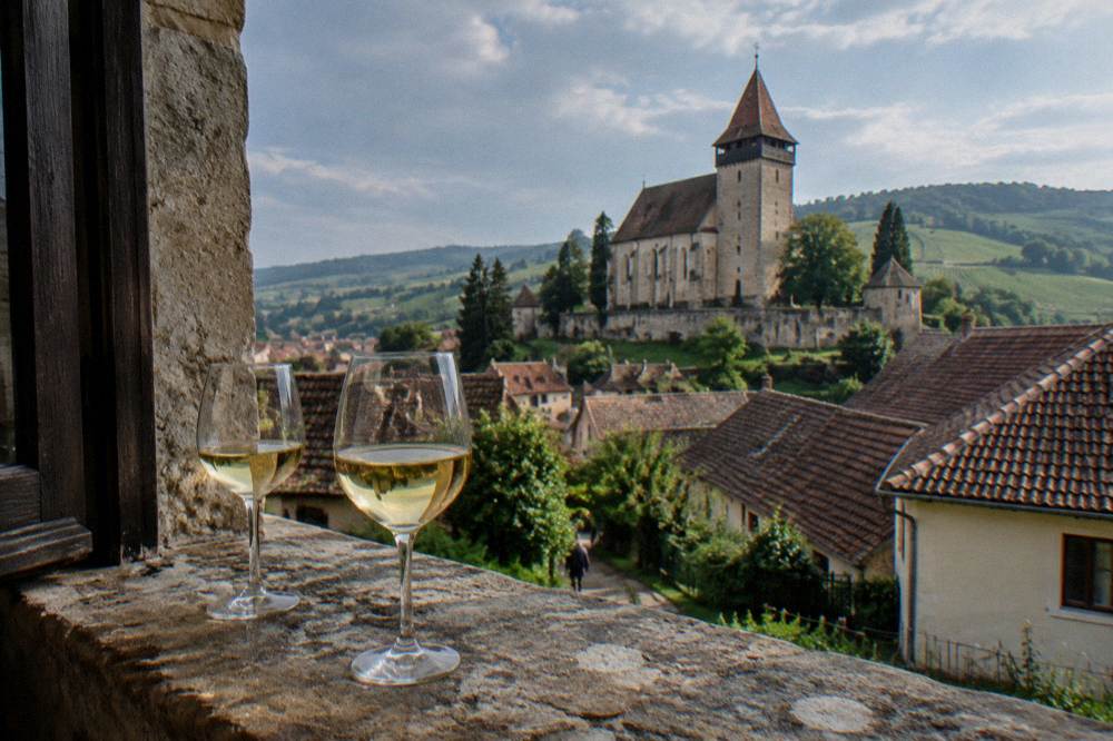 Two glasses of white wine rest on a wide stone window sill