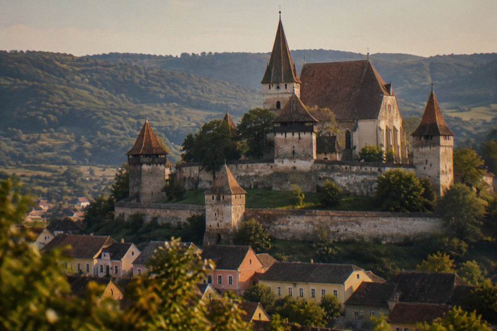 A fortified church with tall defensive walls standing above a Transylvanian village
