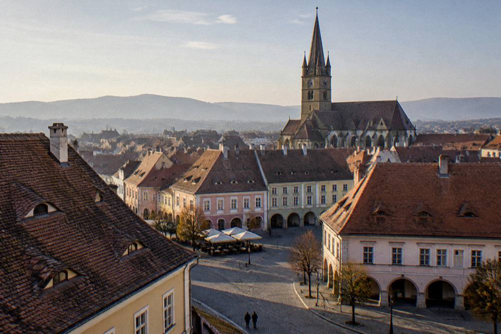 The tall bell tower of a Gothic church rising above red rooftops in Sibiu