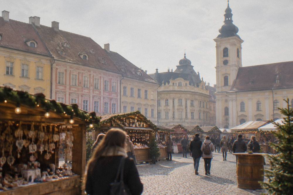 A festive market square with wooden stalls and lights in the main square of Sibiu
