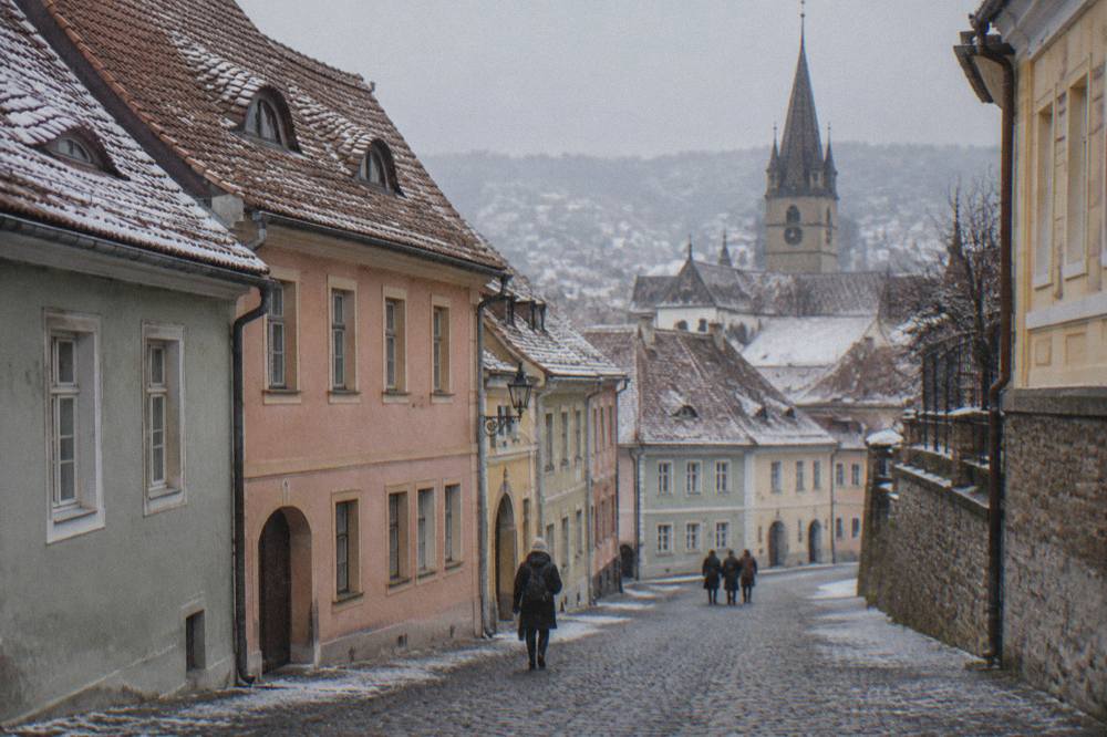 A cobbled lane in the Sibiu Upper Town sloping gently past pastel-coloured houses with attic windows