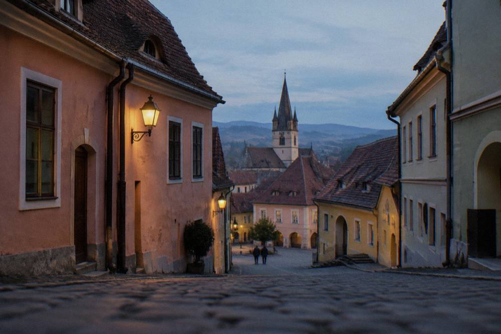 Pastel-coloured burgher houses with steep tiled roofs seen from a narrow street in Sibiu