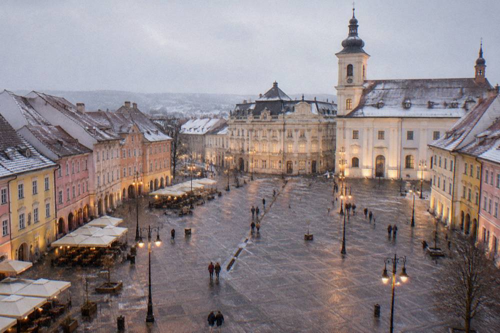 Rows of restored pastel-coloured merchant houses lining a large pedestrian square at dusk