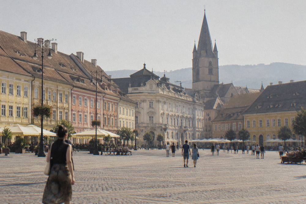 A Gothic church tower rising above red-tiled rooftops in an old Transylvanian town
