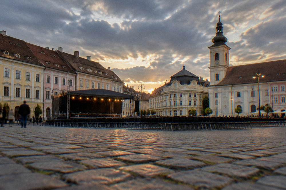 A lit stage set on a stone square at dusk