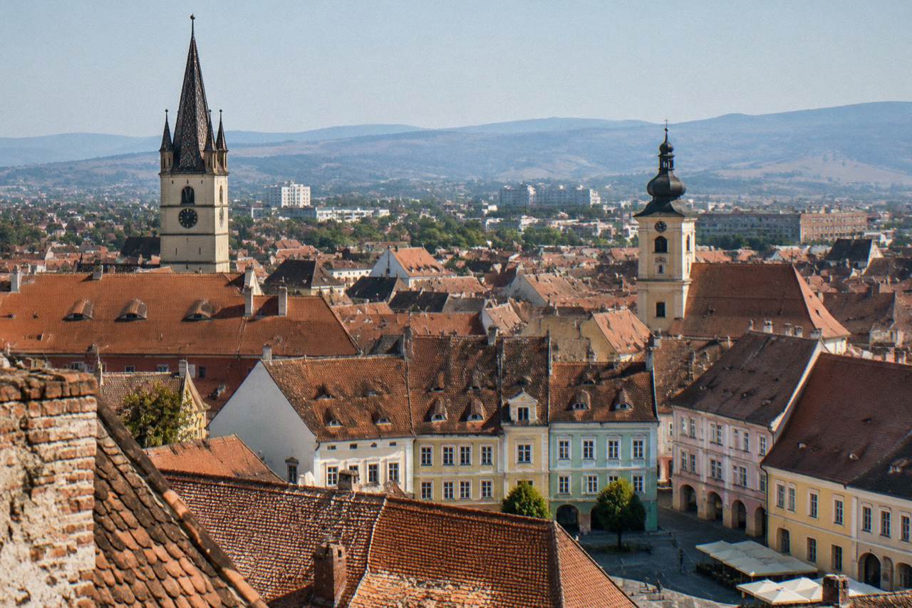 Old town rooftops of Sibiu seen from above, with coloured tiles and church towers