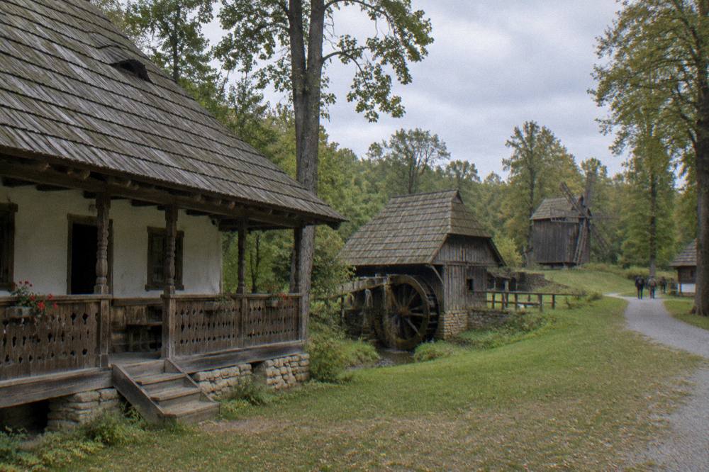 Open-air museum houses with wooden porches in a forest clearing